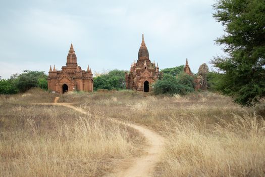 BAGAN, NYAUNG-U, MYANMAR - 2 JANUARY 2020: A dirt rail leading towards the historical buddhist temples in the distance