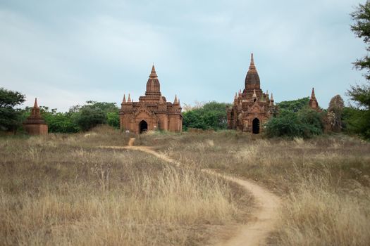 BAGAN, NYAUNG-U, MYANMAR - 2 JANUARY 2020: A dirt rail leading towards the historical buddhist temples in the distance