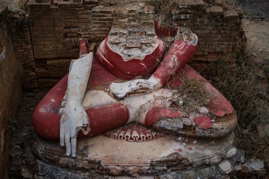 View of an old and historical ruined sitting buddha statue in red from above in Bagan, Myanmar
