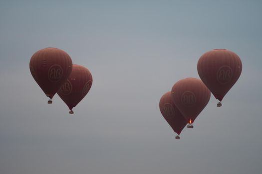 BAGAN, NYAUNG-U, MYANMAR - 2 JANUARY 2020: Five red hot air balloons rises high in the sky together for tourists