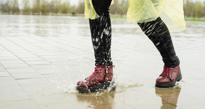 woman running on asphalt in rainy weather. Close up of legs and shoes splashing in puddles.