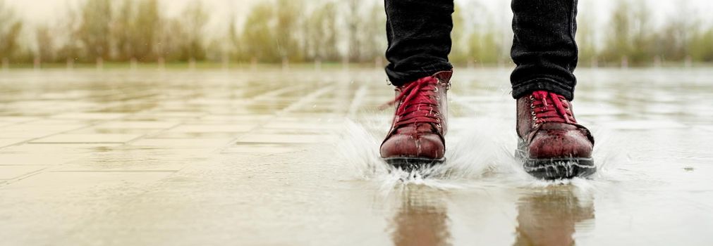 woman running on asphalt in rainy weather. Close up of legs and shoes splashing in puddles.