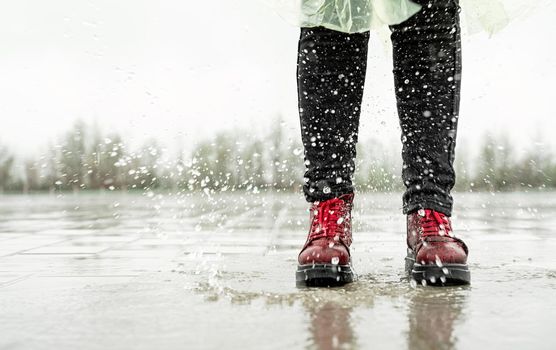 woman running on asphalt in rainy weather. Close up of legs and shoes splashing in puddles.