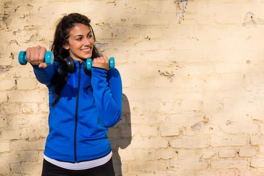 Beautiful woman exercising  with weights outdoor.