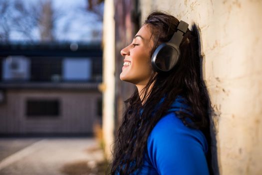 Beautiful sporty woman with headphones  enjoys listening music outdoor.