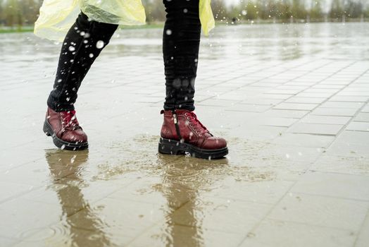 woman running on asphalt in rainy weather. Close up of legs and shoes splashing in puddles.