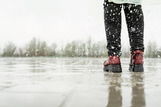 woman running on asphalt in rainy weather. Close up of legs and shoes splashing in puddles.