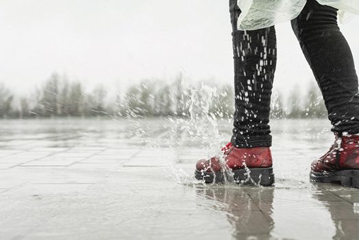 woman running on asphalt in rainy weather. Close up of legs and shoes splashing in puddles.