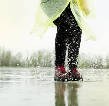 woman running on asphalt in rainy weather. Close up of legs and shoes splashing in puddles.