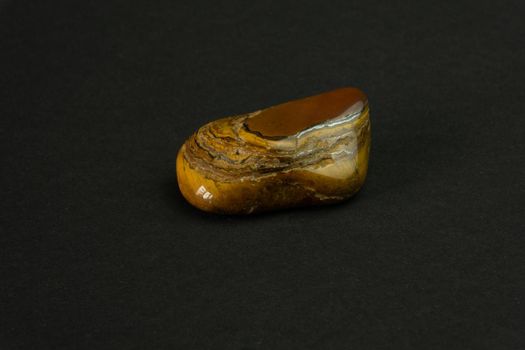 Tiger's eye stone from Republic of South Africa RSA. Natural mineral stone on black background. Mineralogy, geology, magic of stones, semi-precious stones and samples of minerals. Close-up macro photo.