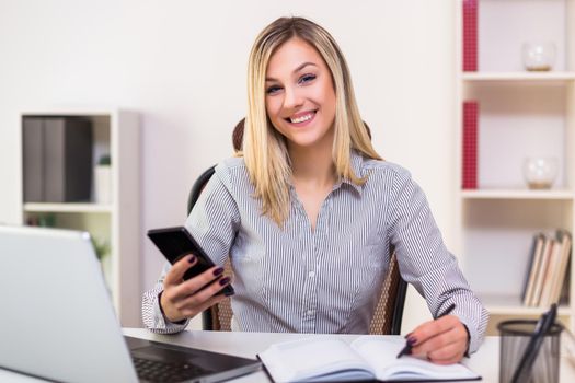 Businesswoman using mobile phone while working in her office.