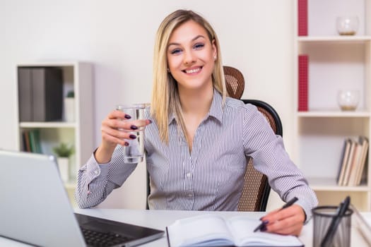 Businesswoman drinking water while working in her office.
