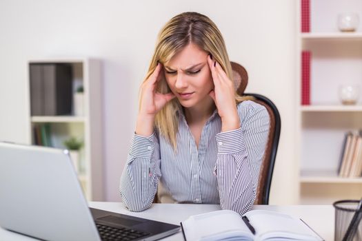 Businesswoman having headache while working in her office.