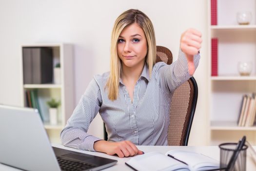 Businesswoman showing thumb down while working in her office.