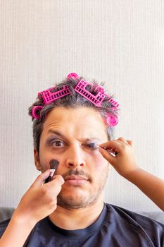 Handsome father is being makeup by the hands of his daughters