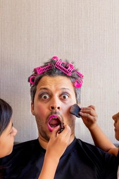 Handsome father is being makeup by the hands of his daughters