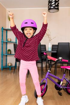 Little girl playing her bicycle in the living room of the apartment during quarantine