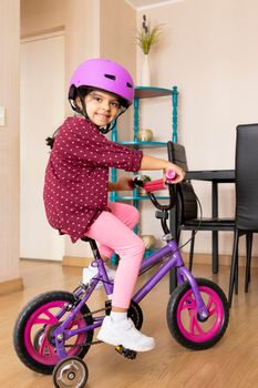Little girl is riding a bicycle in her living room