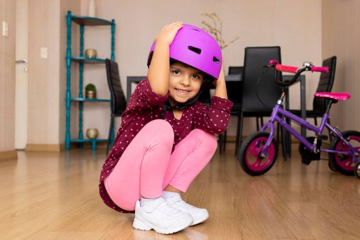 Little girl playing her bicycle in the living room of the apartment during quarantine