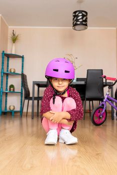 Little girl playing her bicycle in the living room of the apartment during quarantine