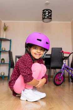 Little girl playing her bicycle in the living room of the apartment during quarantine