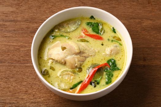 Chicken drumstick green curry in round bowl on old wooden table, thai traditional cuisine