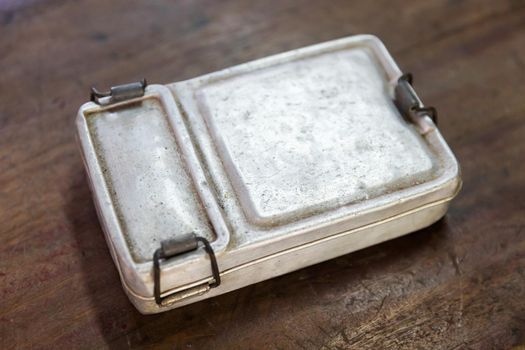 Closeup old and rusty aluminium lunch box on wooden table, old fashion vintage retro style