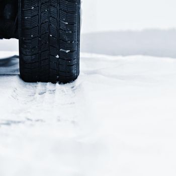 Car in winter. Tire on a snowy road in bad weather.