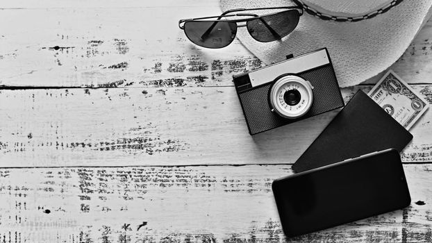 Items for summer vacation: a camera, passport,smartphone, money, hat, sunglasses. Wooden background, top view with Copy space. Beautiful summer concept for travel and vacation-holidays.