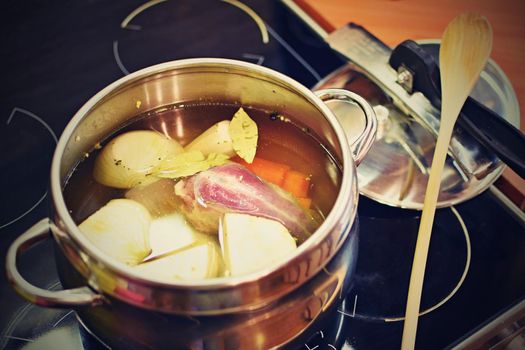 Preparing homemade chicken soup - broth. Pot on the stove in the kitchen with ingredients for cooking.