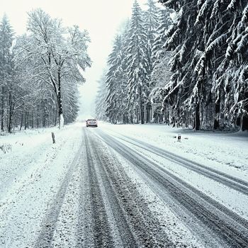 Snowy winter road with car. Dangerous car driving in the mountains in the winter. Concept for transportation, cars and travel.