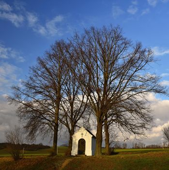 Beautiful little chapel with landscape and trees at sunset. Nebovidy - Czech Republic.