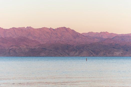 Sunset over the Red sea with pink orange mountains on the background. Eilat, Aqaba, Israel, Jordan . High quality photo