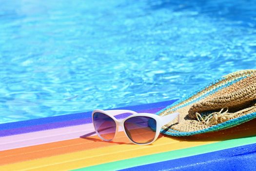 Sunglasses, lilo and hat on the water in hot sunny day. Summer background for traveling and vacation. Holiday idyllic.