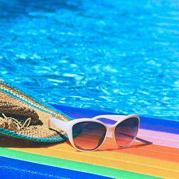 Sunglasses, lilo and hat on the water in hot sunny day. Summer background for traveling and vacation. Holiday idyllic.