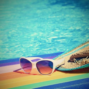 Sunglasses, lilo and hat on the water in hot sunny day. Summer background for traveling and vacation. Holiday idyllic.