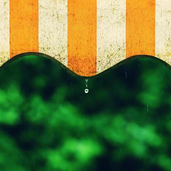 Rain. Awning on a balcony and drops of water on a natural colorful background during a spring day