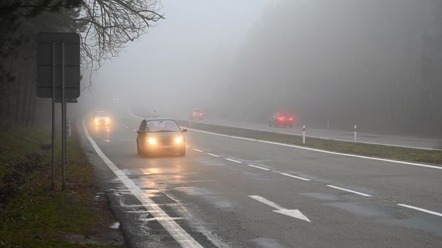 Bad weather driving - foggy hazy country road. Motorway - road traffic. Winter time.