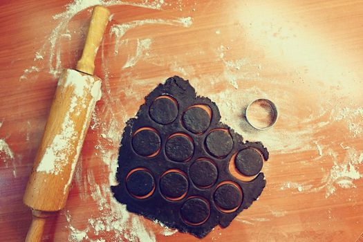 Baking Christmas cookies. On the table, flour, roller and dough.