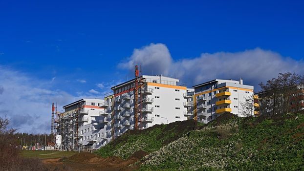 Construction of new homes. Concept for industry. Crane and blue sky with clouds and sun. Building construction site