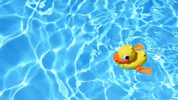 Yellow rubber duck on the water in hot sunny day. Summer background for traveling and vacation. Holiday idyllic.