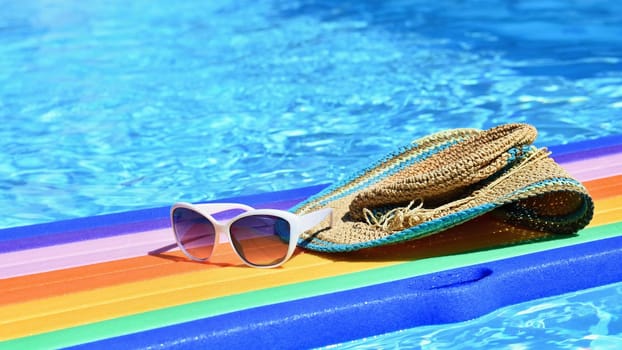 Sunglasses, lilo and hat on the water in hot sunny day. Summer background for traveling and vacation. Holiday idyllic.