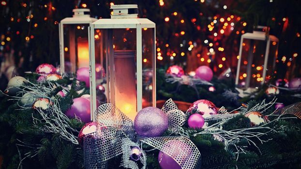 Christmas background. Lanterns with purple ornaments on a Christmas tree. Beautiful blurred abstract colorful lights in the background. Concept for holidays, winter time and a happy new year.