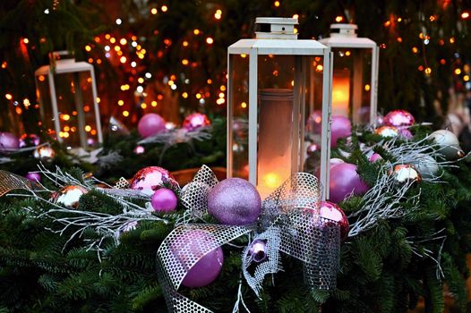 Christmas background. Lanterns with purple ornaments on a Christmas tree. Beautiful blurred abstract colorful lights in the background. Concept for holidays, winter time and a happy new year.