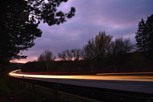 Night photo traffic on the road. Evening landscape with cars. Cars with lights and blurred color lines.