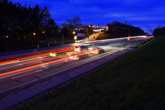 Night photo traffic on the road. Evening landscape with cars. Cars with lights and blurred color lines.