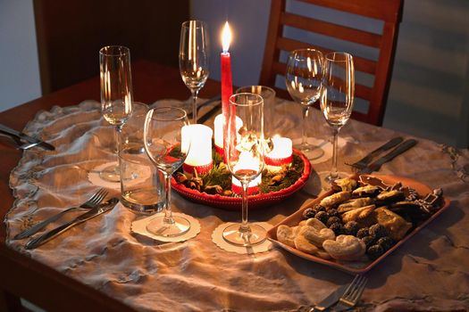 Beautifully set table for Christmas holidays. Candies, candles and Christmas decorations - decorated home on Christmas Eve.