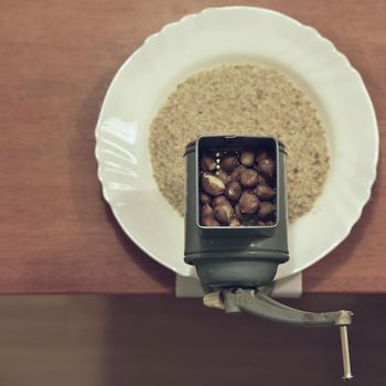 Nice old mill on a table with a plate. Milling nuts for baking sweet desserts and Christmas cookies. View from above.