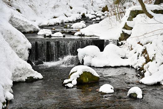 Winter stream with stones and snow. A beautiful winter concept for winter and frost.