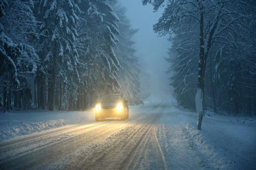 Snowy winter road with car. Dangerous car driving in the mountains in the winter. Concept for transportation, cars and travel.